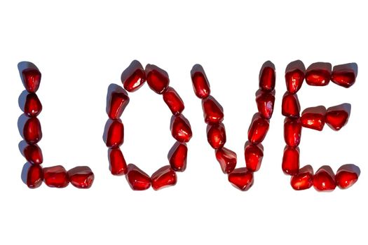 Love word from red pomegranate seeds. Valentine's day concept. Sign pattern. Isolated on white background.