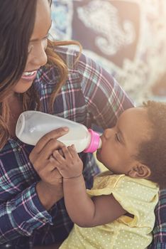 Its feeding time. a young mother feeding her baby girl at home