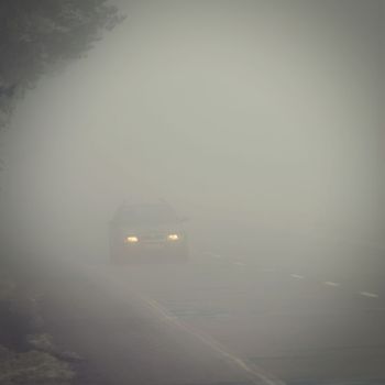 Cars in the fog. Traffic on the road in winter in bad weather. Dangers of driving cars.