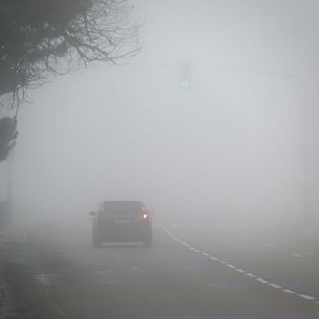 Cars in the fog. Traffic on the road in winter in bad weather. Dangers of driving cars.