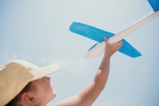 Kid playing with toy airplane. Children dream of travel by plane. Happy child girl has fun in summer vacation by sea and mountains. Outdoors activities at background of blue sky. Lifestyle moment