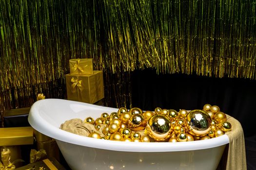 Bathtub full of golden balls. Vintage bright bathroom decorated with festive golden balls. New Year, Christmas bathroom interior