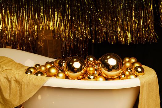 Bathtub full of golden balls. Vintage bright bathroom decorated with festive golden balls. New Year, Christmas bathroom interior