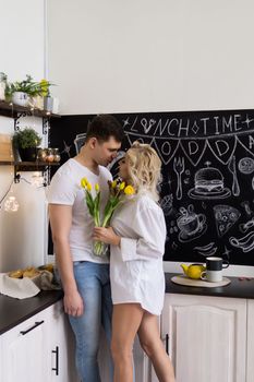 Love is quarantined during the Coronavirus. This is the new normal. A young couple in love in their home kitchen