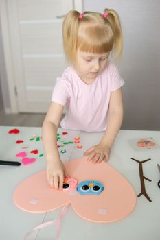 A blogger girl makes a felt craft for Valentine's Day in the shape of a heart. The concept of children's creativity and handmade