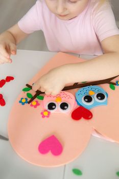 A blogger girl makes a felt craft for Valentine's Day in the shape of a heart. The concept of children's creativity and handmade