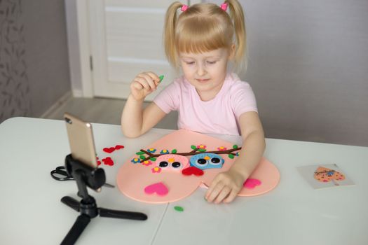 A blogger girl makes a felt craft for Valentine's Day in the shape of a heart. The concept of children's creativity and handmade