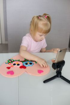 A blogger girl makes a felt craft for Valentine's Day in the shape of a heart. The concept of children's creativity and handmade