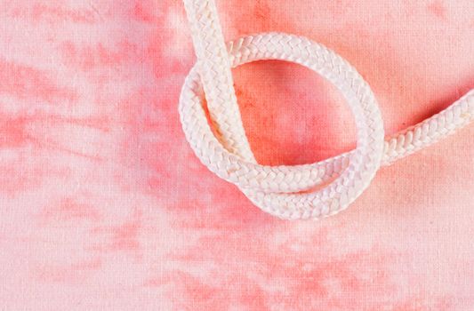 Tied white rope , against red background , nautical rope 