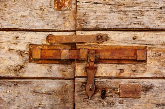 Old vintage rusty iron latch on cracking door ,the door is made  of horizontal wooden boards