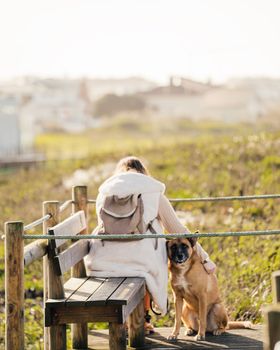 young girl sitting on a park bench next to her dog, winter, outdoors, alone.