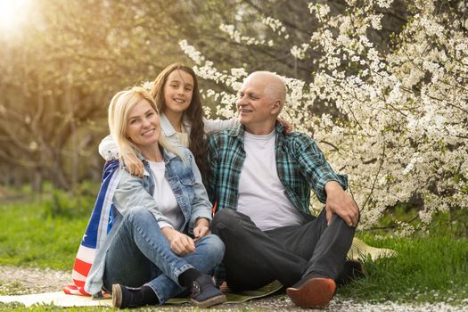 Portrait of happy family celebrating 4th July Independence Day holding silhouette usa national flag against park.