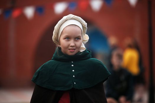 Portrait of a young girl in a medieval castle. A little girl in medieval dress walking through a yard. historical reconstruction. 14.05,2022. Yoshkar-Ola, Russia.
