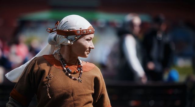 Medieval archery tournament. A woman shoots an arrow in the medieval castle yard. Woman in medieval dress with a wooden bow in her hands. historical reconstruction. 14.05,2022. Yoshkar-Ola, Russia.