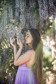 Thoughtful happy mature woman surrounded by chinese wisteria.