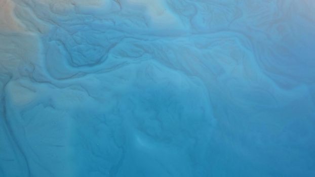 Top view of the turquoise water of a mountain lake. Clean clear water with streaks on the bottom. Patterns from a mountain river. The color shimmers from blue-green to blue. Trees in the water. Issyk