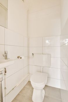 a bathroom with white tiles on the walls, and a toilet in the corner next to the sink is visible