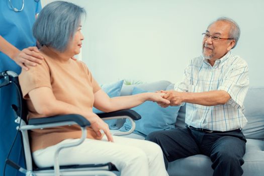 A contented senior couple and their in-home nurse. Elderly female in wheelchair with her young caregiver.