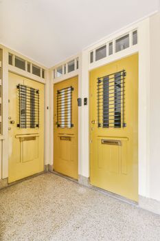 an empty room with yellow doors and black shutters on the front door that leads to another room in the background