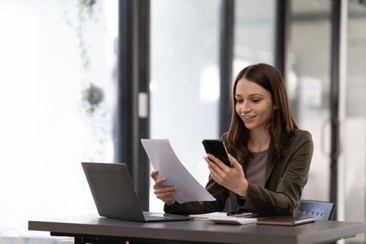 Business woman using smartphone for do math finance on wooden desk in office, tax, accounting, financial concept