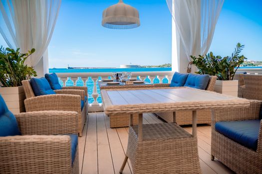 Cafe sea no one. Empty street cafe with wicker furniture on the beach. Overlooking the sea on a sunny summer day, coastline on the horizon and blue sky