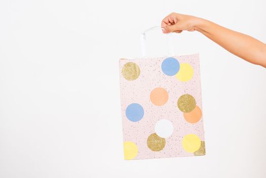 Closeup women hand holding a colorful pink shopping bag circular pattern, studio shot isolated on white background, female holds in hand white clear empty blank craft paper gift bag for purchases