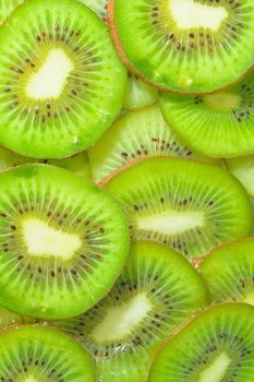 Close-up view of the green kiwi fruit slices in water background. Texture of cooling fruit drink with macro bubbles on the glass wall. Flat design. Vertical image.