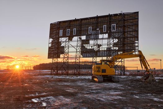 Abandoned outdoor drive in movie theater at sunset with excavator ready for demolition in Elmvale