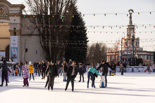 KYIV, UKRAINE - 2 January, 2023: Ice-skating people. People have fun in ice arena at the city ice rink. New Years holidays in city Kyiv