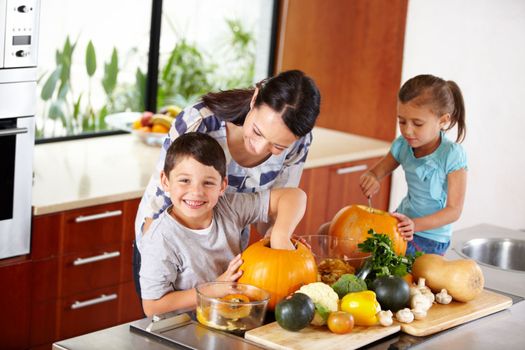 I think its ready. a mother helping her children carve pumpkins for halloween