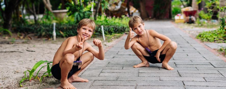 Boy blond freckles squatting sit smiling show gesture thumbs up shirtless bare chested shorts nature.