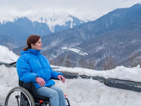 Caucasian woman in a wheelchair travels in the mountains in winter