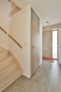 an empty room with wood flooring and wooden staircase leading up to the second floor in a door is on the right hand side