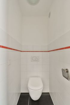 a white toilet in a bathroom with red and white tiles on the wall behind it is an open shower stall