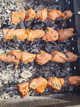 Pork kebab on skewers with herbs over coals top view.Texture or background.