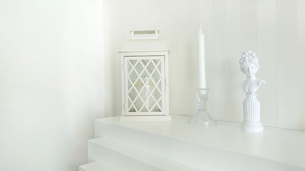 Texture or background. Home decor.A statuette of a woman, a lantern and a candlestick stand on a white fireplace