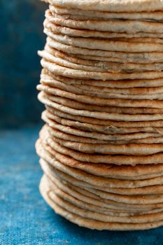 Flatbread lavash, chapati, naan, heap of tortilla on a blue background Homemade flatbread stacked