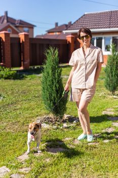 Young woman plays with her dog on the grass on backyard. The concept of animals and friendship or pet owner and love.