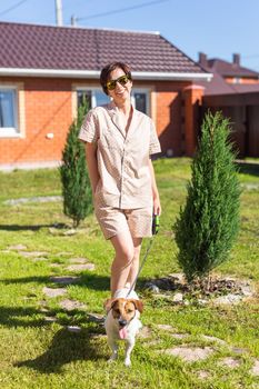 Young woman plays with her dog on the grass on backyard. The concept of animals and friendship or pet owner and love.