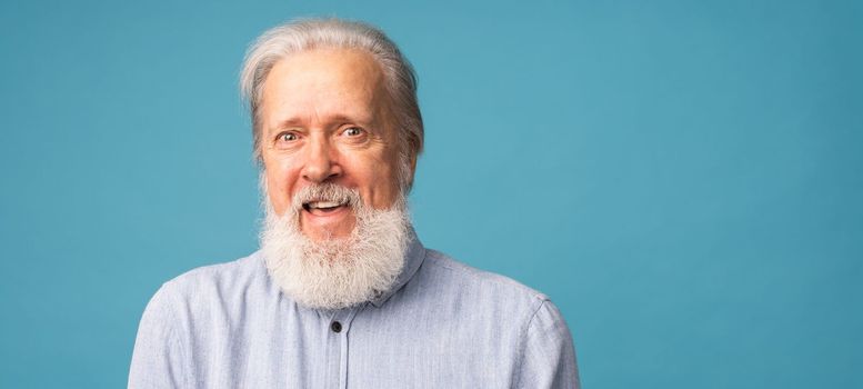 Banner portrait of surprised grey hair beard grandfather old man over blue colour background with copy space