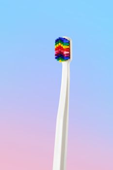 White toothbrush with multicolored bristles. Bristles in all colors of the rainbow. Rainbow toothbrush with white knob. Fashionable oral care