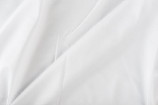 White wrinkled fabric. White fabric with large folds top view. For overlay texture or design