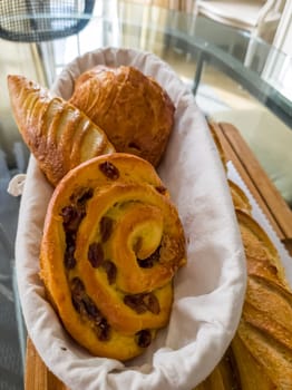 Delicious pain aux raisins spiral buns with raisins and custard close-up in a plate on the table. horizontal.