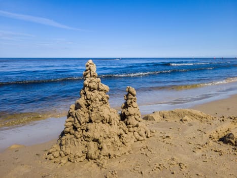 Built House sand castle with towers on the south shore of the sandy beach blue sea.
