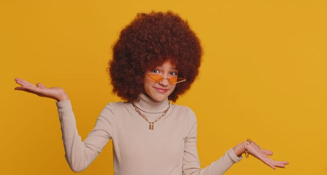 I dont know what to say. Confused young funny school girl feeling embarrassed about ambiguous question having doubts no idea, being clueless and uncertain. Teen female child kid on yellow background