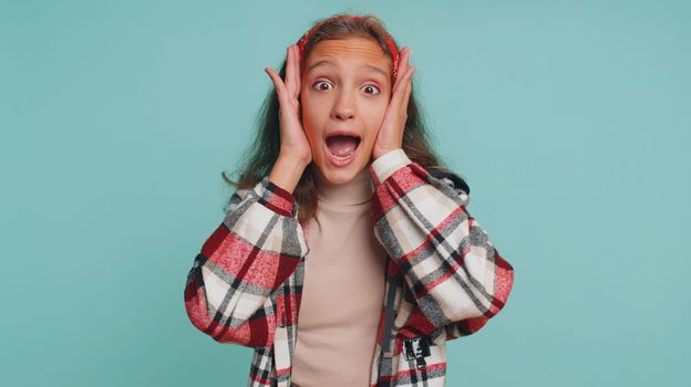 Oh my God, Wow. Young teenager child girl kid looking surprised at camera with big eyes, shocked by sudden victory, game winning lottery goal achievemen good news. Preteen children on blue background