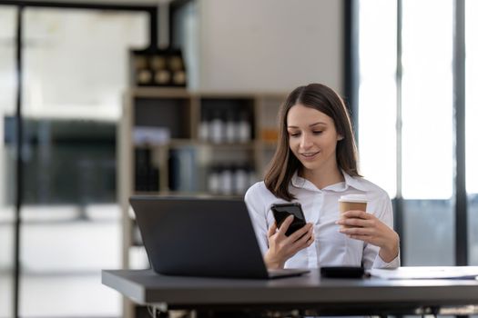 Business woman using smartphone for do math finance on wooden desk in office, tax, accounting, financial concept.