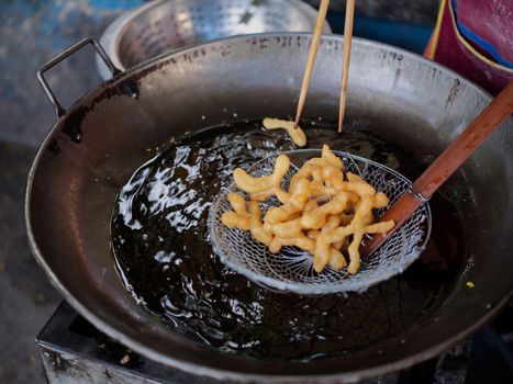 Die cut of Deep fried Chinese Doughnut in an big oil pan