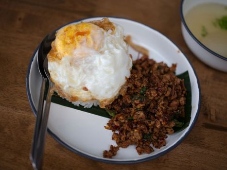 Pad Krapow MOO - Thai Basil Pork with Rice and fried Egg  background. Thai cuisine dish with minced  pork , basil, soy and oyster sauces. Thai Food Copy space