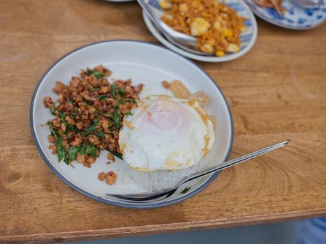 Pad Krapow MOO - Thai Basil Pork with Rice and fried Egg  background. Thai cuisine dish with minced  pork , basil, soy and oyster sauces. Thai Food Copy space